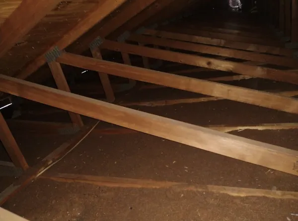 Attic space before cleanup showing old contaminated insulation