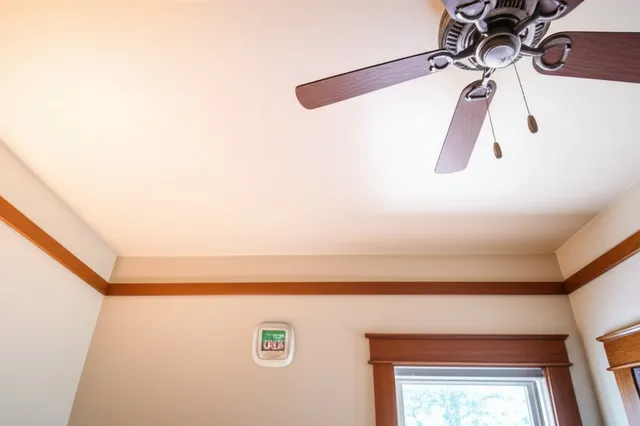 Interior of an upstairs bedroom with sunlight streaming through windows, showing the gap between ceiling drywall and attic insulation above